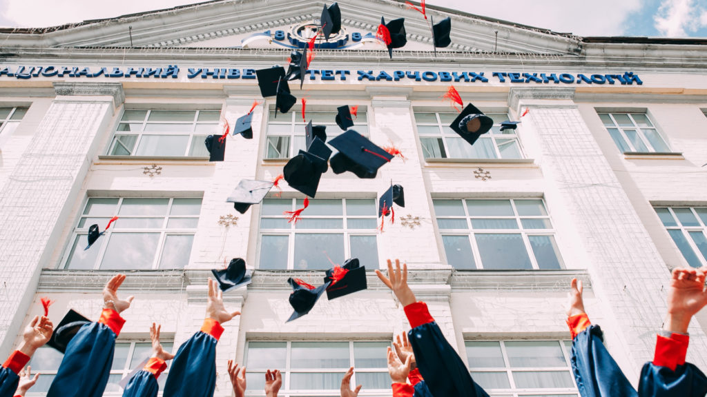college graduates throwing hats