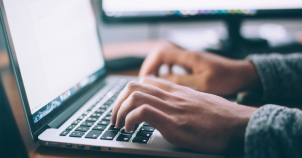 man typing at laptop on desk