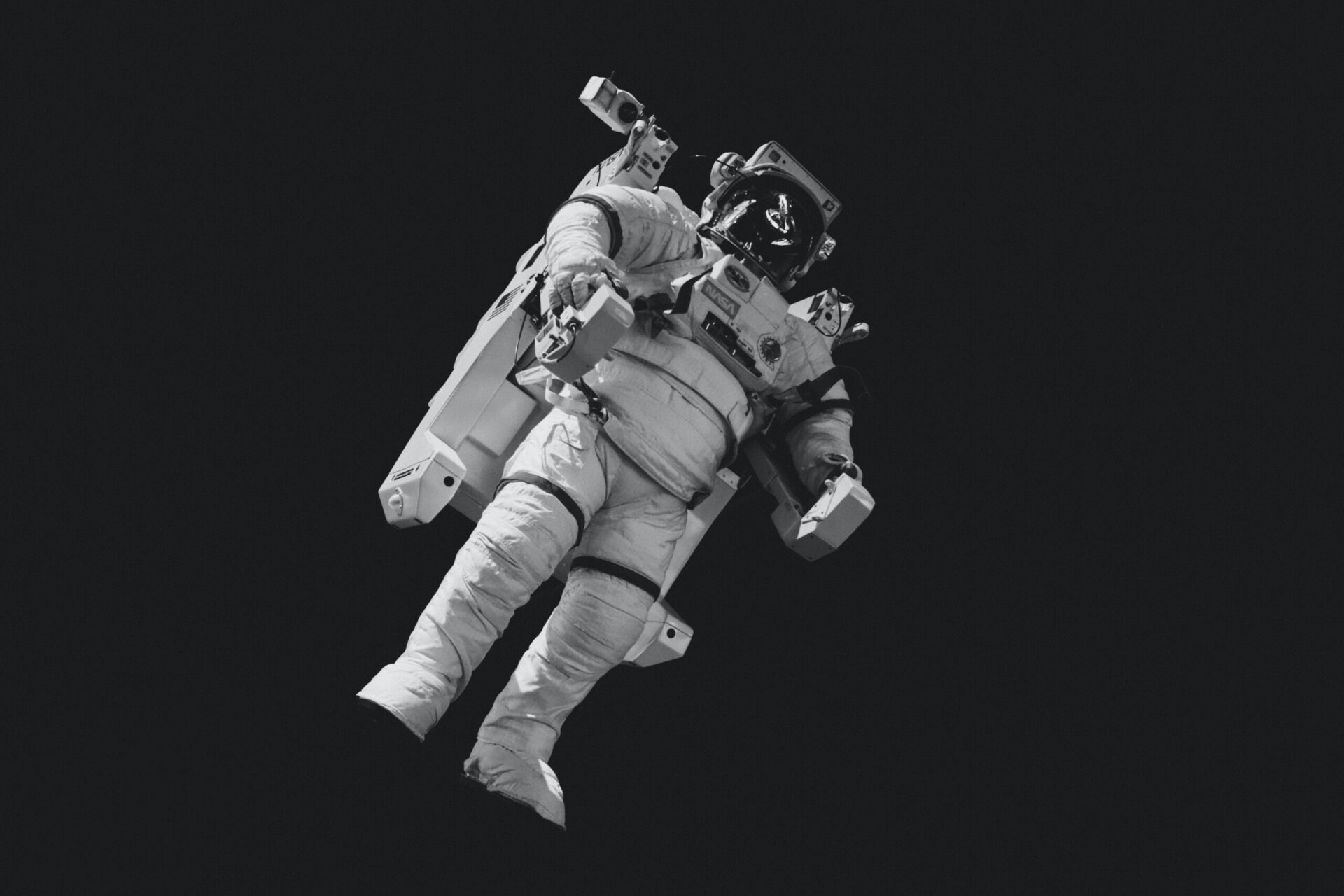 An astronaut in a spacesuit is suspended in space against a black background.