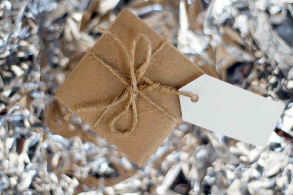 A brown package wrapped with brown twine with a blank tag rests on top of a metallic surface.