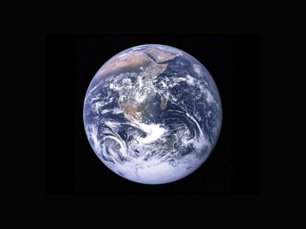 A view of Earth from space, with swirls of white clouds over green and brown masses of land and blue seas.